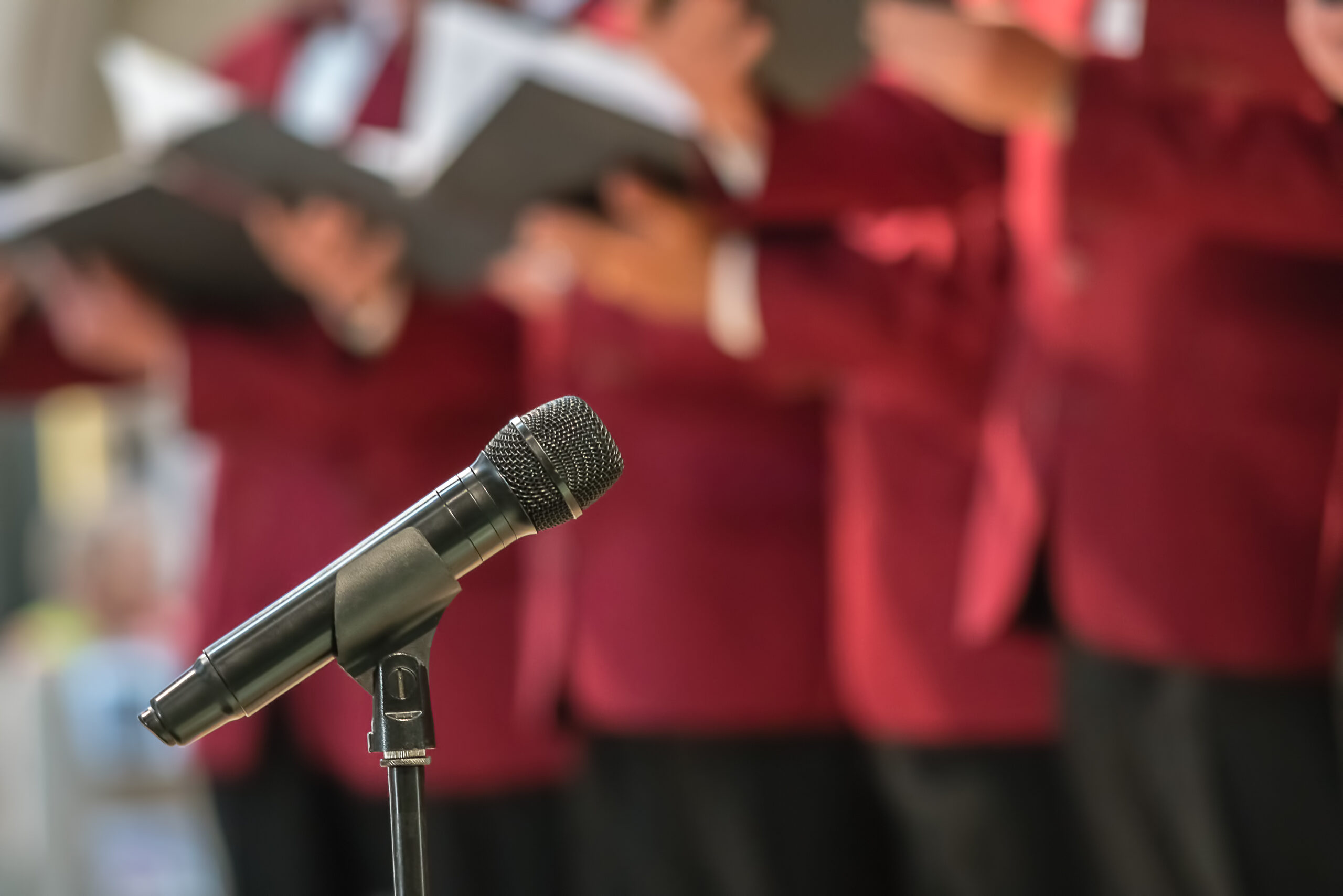 Microphone on a stand in front of mens choir members holding singing book while performing in a cathedral in Rochester, Kent, UK